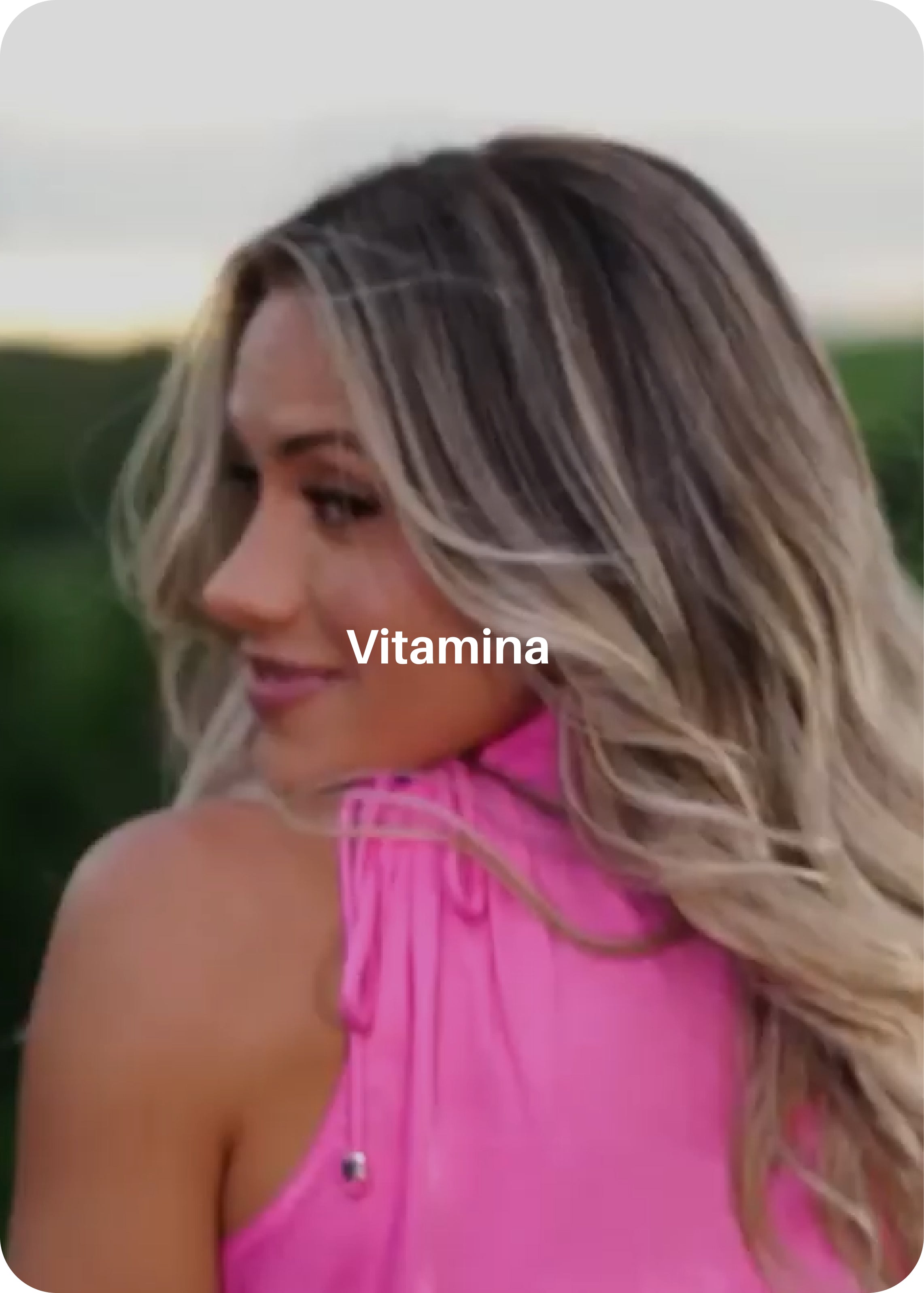 Mulher de costas com rosto em perfil sorrindo ao fundo com texto branco no centro da imagem "Vitamina"